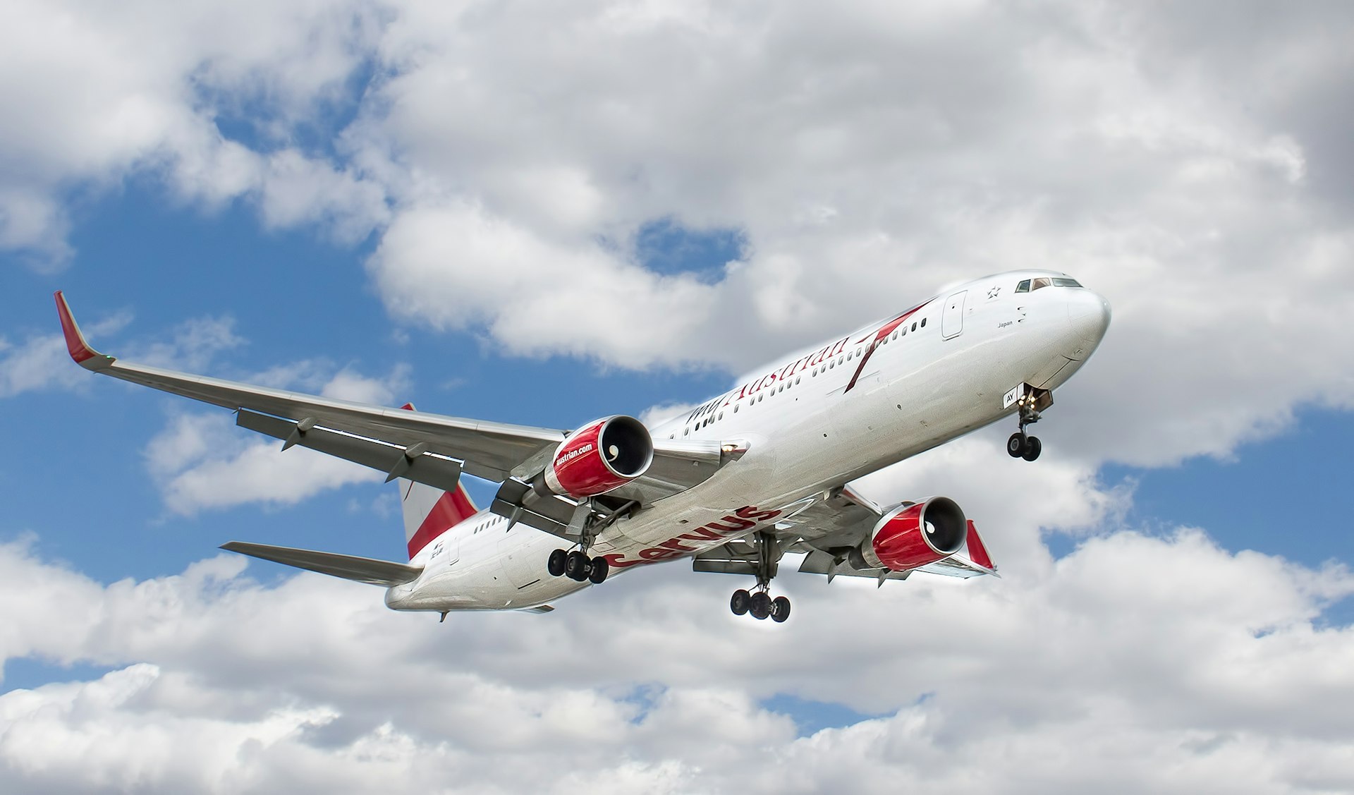 white and red flying airplane under white clouds